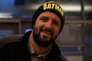 Paul Gutierrez smiling for the camera wearing a beanie of his favorite superhero.