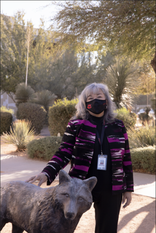 Patricia Goolsby poses with the Combs Coyote located outside the principals office.