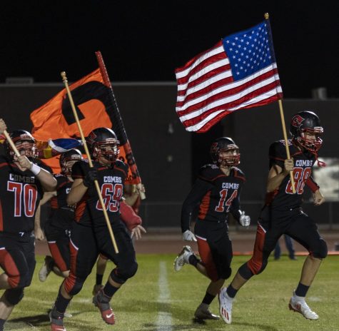 Junior Ty Strebeck leads the pack with the american flag to the field in the final game.
