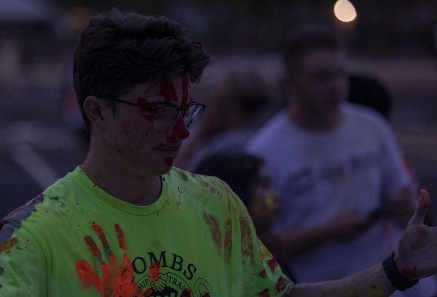 At the beginning of the glow in the dark color dance, senior Mack Beach has hand prints placed all over him.
